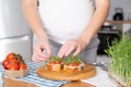 Pregnant young woman preparing healthy sandwiches with microgreens and vegetables. Food rich in fiber Royalty Free Stock Photo