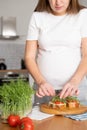 Pregnant young woman preparing healthy sandwiches with microgreens and vegetables. Food rich in fiber Royalty Free Stock Photo