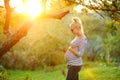 Pregnant young woman on second trimester posing in sunny garden