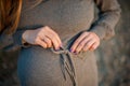 Pregnant young woman standing on the beach in a gray knitted dress. Pregnancy concept Royalty Free Stock Photo