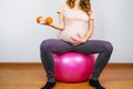 Pregnant girl doing exercises with dumbbell sitting on fit ball. Active pregnancy and maternity fitness. Royalty Free Stock Photo