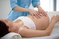 Mom-to-be young woman with beautiful skin lying on bed having relaxing massage Royalty Free Stock Photo