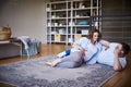 pregnant young woman in a white T-shirt is lying on the floor with her husband in the bedroom on the carpet