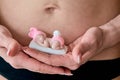 Pregnant young woomen holds a figurine of soap in the shape of a newborn baby girl. Royalty Free Stock Photo