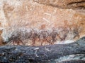 Prehistoric painting of men in actions on rock painted with red colour by human who live in the area over thousand year ago Royalty Free Stock Photo