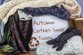 Preloved clothes in a box marked with board sign Autumn clothes swap and recycle textiles symbol