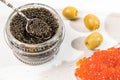 Premium black and red caviar in a glass jar. A vintage spoon full of black caviar. decorated with olives.