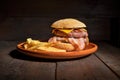 Premium grilled beef hamburger with bacon, cheese and French fries. Delicious American burger on wooden background.