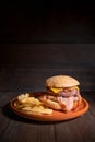 Premium grilled beef hamburger with bacon, cheese and French fries. Delicious American burger on wooden background.