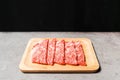 Premium Rare Slices sirloin Wagyu A5 beef with high-marbling texture on a wooden plate with a black background. Served for