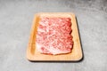 Premium Rare Slices sirloin Wagyu A5 beef with high-marbling texture on a wooden plate with a black background.