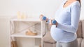 Closeup of pregnant woman holding blue dumbbells