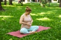 Prenatal yoga. Caucasian pregnant woman doing butterfly pose in the park. Royalty Free Stock Photo