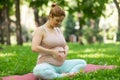 Prenatal yoga. Caucasian pregnant woman doing butterfly pose in the park. Royalty Free Stock Photo