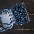 Prepackaged blueberries in a plastic container on a wooden background Royalty Free Stock Photo