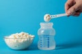 Preparation of baby milk food for feeding babies. Powdered milk mixture with vitamins and minerals on a blue background