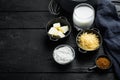 Preparation of bechamel cheese white sauce, on black wooden table background, with copy space for text