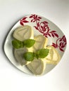Preparation of biscuit rolls. On the table stand a plate with a ready sliced roll, decorated with lemon bald leaves.