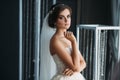 Preparation of the bride on a wedding day. Beautiful brunette girl in a white luxury dress, with earrings, make-up and Royalty Free Stock Photo