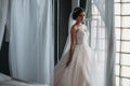 Preparation of the bride on a wedding day. Beautiful brunette girl in a white luxury dress, with earrings, make-up and Royalty Free Stock Photo