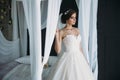 Preparation of the bride on a wedding day. Beautiful brunette girl in a white luxury dress, with earrings, make-up and Royalty Free Stock Photo