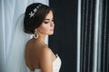 Preparation of the bride on a wedding day. Beautiful brunette girl in a white luxury dress, with earrings, make-up and Royalty Free Stock Photo