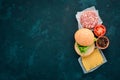 Preparation of burger. Meat, tomatoes, onions. On a white wooden background.