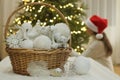 Preparation for Christmas. White Christmas ornaments in wicker basket. Girl with santa hat decorating Christmas tree.