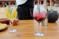 Preparation of citrus gin and tonic and red berries on wooden table, waitress serves food and drinks