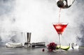 Preparation Classic alcoholic cocktail cosmpolitan with vodka, liqueur, cranberry juice, lime, ice and orange zest, gray bar Royalty Free Stock Photo