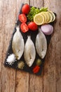 Preparation for cooking Sarpa salpa fish with lemon, vegetables and spices close-up on a slate board. Vertical top view Royalty Free Stock Photo