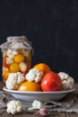 Preparation of fermented vegetables. Fresh tomatoes,cauliflower in a plate in the foreground. Royalty Free Stock Photo