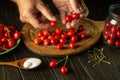 Preparation of fruit drink from fresh cherries. Cook's hands sorting cherry berries before preparing a sweet drink in a jar