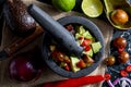 Preparation of guacamole in a traditional stone mortar with all its ingredients chopped avocados, lime, onion, tomatoes and chili Royalty Free Stock Photo