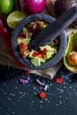 Preparation of guacamole in a traditional stone mortar with all its ingredients chopped avocados, lime, onion, tomatoes and chili Royalty Free Stock Photo