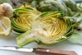 Preparation of heads of fresh raw artichokes plants from artichoke plantation in Argolida, Greece ready to cook with lemon