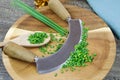 Preparation of herbs for meal:  brown wood cutting board with chefÃÂ´s mincing knife, chopped green chives and wooden spoon Royalty Free Stock Photo