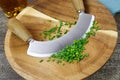 Preparation of herbs for meal: isolated brown wood cutting board with chefÃÂ´s mincing knife, chopped green chives Royalty Free Stock Photo