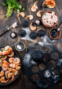 Preparation of Italian black ravioli with seafood shrimps and crabs on black plate, gray stone slate background. Top