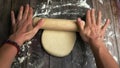 Preparation for making pizza, the dough is rolled out with a rolling pin by women& x27;s hands, a first-person view. Royalty Free Stock Photo