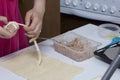 Preparation of meat glomeruli. Stuffed turkey, wrapped in strips of puff pastry. A woman winds a strip of dough on a meat ball Royalty Free Stock Photo