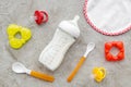 Preparation of mixture baby feeding with infant formula powdered milk in bottle, spoon and toys on gray background top