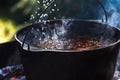 Preparation of pilaf on fire. Tourist bowler with food on bonfire, cooking in the hike, outdoor.