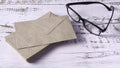 Preparation for Reading: Stack of Kraft Envelopes and Black Eyeglasses on Rustic Desk Royalty Free Stock Photo