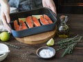 Preparation of salmon. Female hands with a lime slice. A pot with raw salmon steaks.