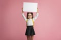 Preparation for school. Smiling little girl with backpack in glasses, holding sign with empty space