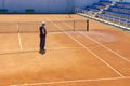 Preparation of a tennis court watering from a hose. A man watering a tennis court