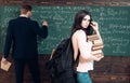 Preparation to exam. Woman student look in glasses with book stack and backpack with teacher man writing on chalkboard