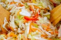 Preparation of vegetarian salad of fresh raw vegetables white cabbage, carrots, red sweet pepper Mixing with two wooden blades. Royalty Free Stock Photo