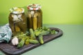 Preparations of pickled cucumbers and gherkins. Jars of pickles and fresh cucumbers on a wooden cutting Board with herbs.